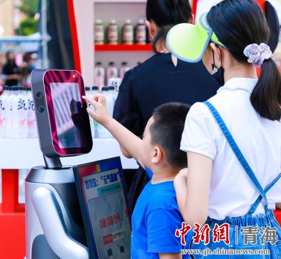 圖為一名小朋友正在和機器人“志愿者”進(jìn)行互動。 沐聞 攝