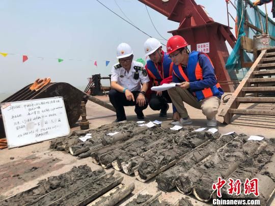 圖為勘察設(shè)計人員與海事局工作人員查看巖芯情況。　魏震 攝