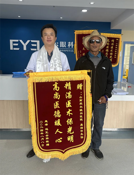 達(dá)瓦老人向吳四華（左）贈(zèng)送錦旗。受訪者供圖