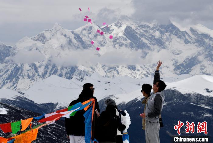 圖為5月14日，游客在西藏林芝色季拉山觀景臺拋灑“隆達(dá)”(風(fēng)馬旗，藏族民眾的一種祈福方式)。　李林 攝