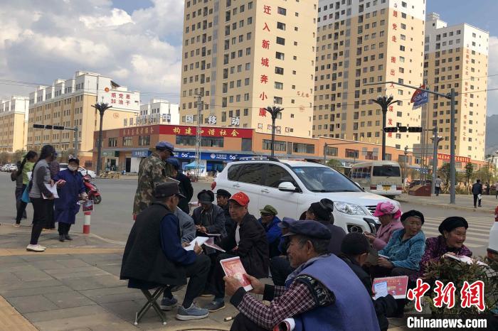 圖為會澤縣城易地扶貧搬遷安置點(diǎn)內(nèi)，老人們聚在廣場上聊天，身后是他們的新家。　繆超 攝