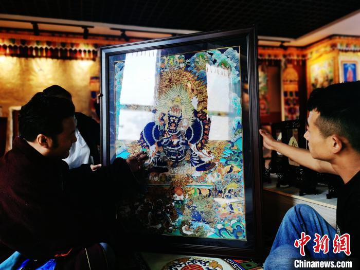 圖為久美尖措(左)與徒弟們展示唐卡作品。　張?zhí)砀?攝