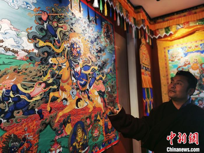 圖為久美尖措展示唐卡作品?！?zhí)砀?攝