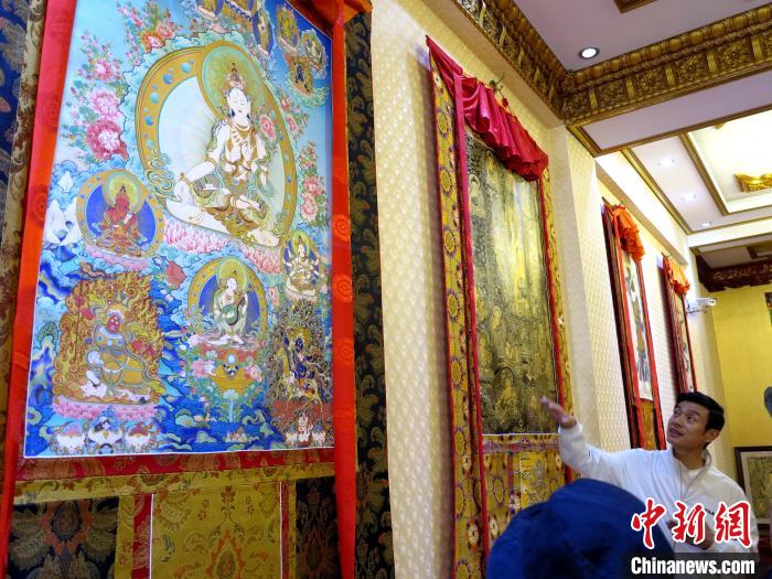 圖為完德尖措展示熱貢龍樹(shù)畫(huà)苑內(nèi)的唐卡。　張?zhí)砀?攝