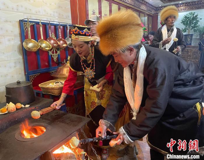 圖為人們在火上烤節(jié)日美食“結(jié)達(dá)”?！∪轿木?攝
