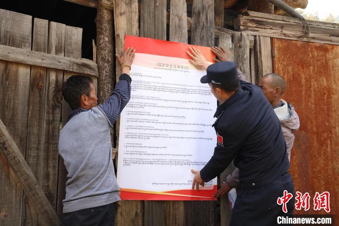 圖為亞?wèn)|邊檢站民警與駐地邊民群眾共同張貼國(guó)家安全知識(shí)教育海報(bào)。　亞?wèn)|邊檢站 供圖